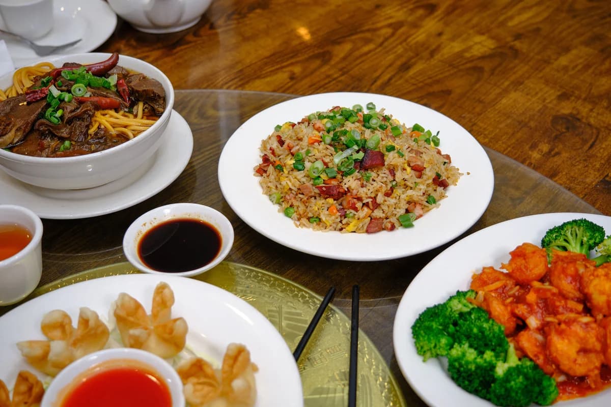 Table of Beijing dishes including fried rice, noodles, dumplings, and vegetables in a local restaurant setting.