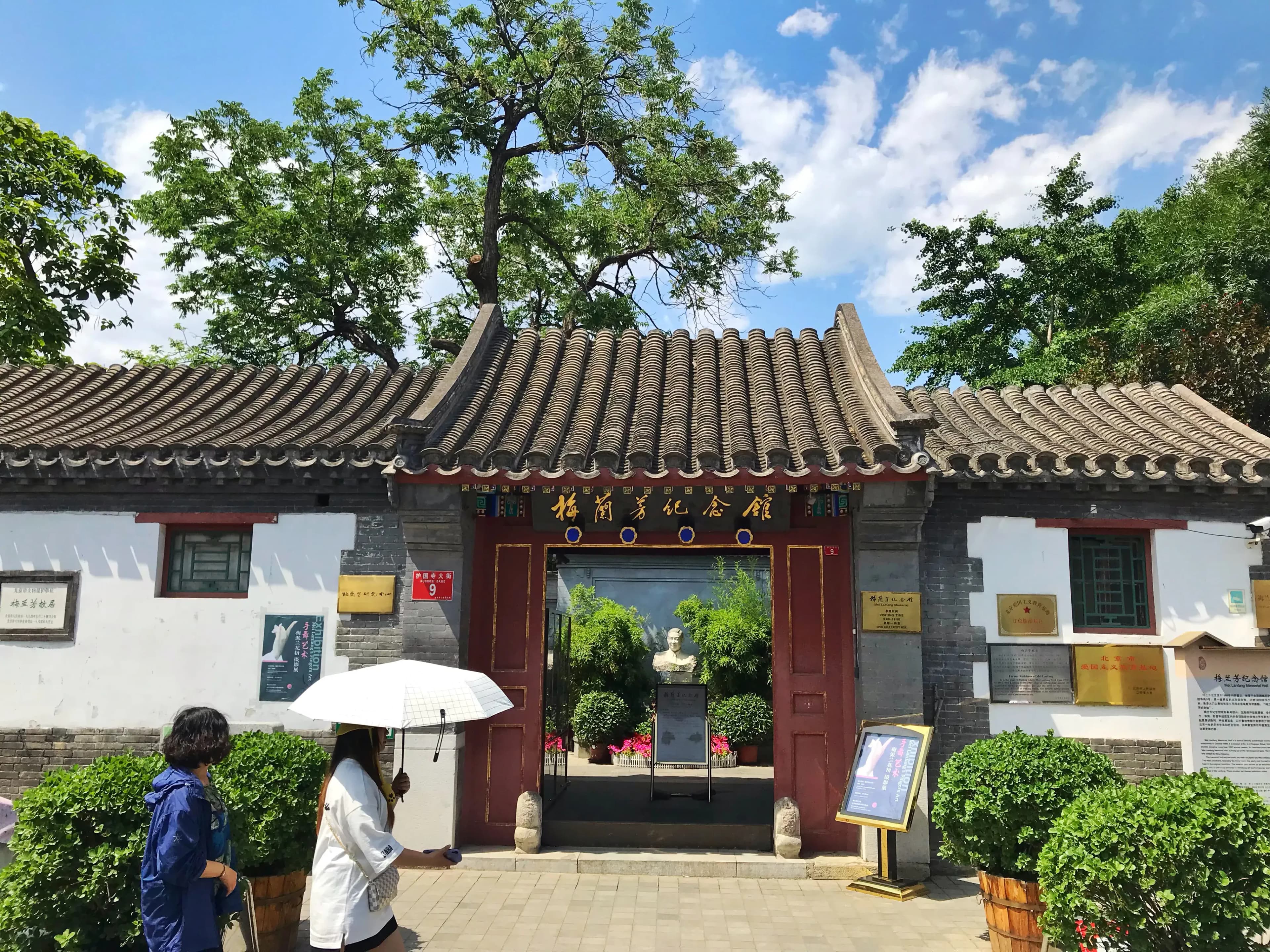 Entrance to Mei Lanfang Memorial with traditional Chinese architecture, tiled roof, and red doors. Visitors walking in front.