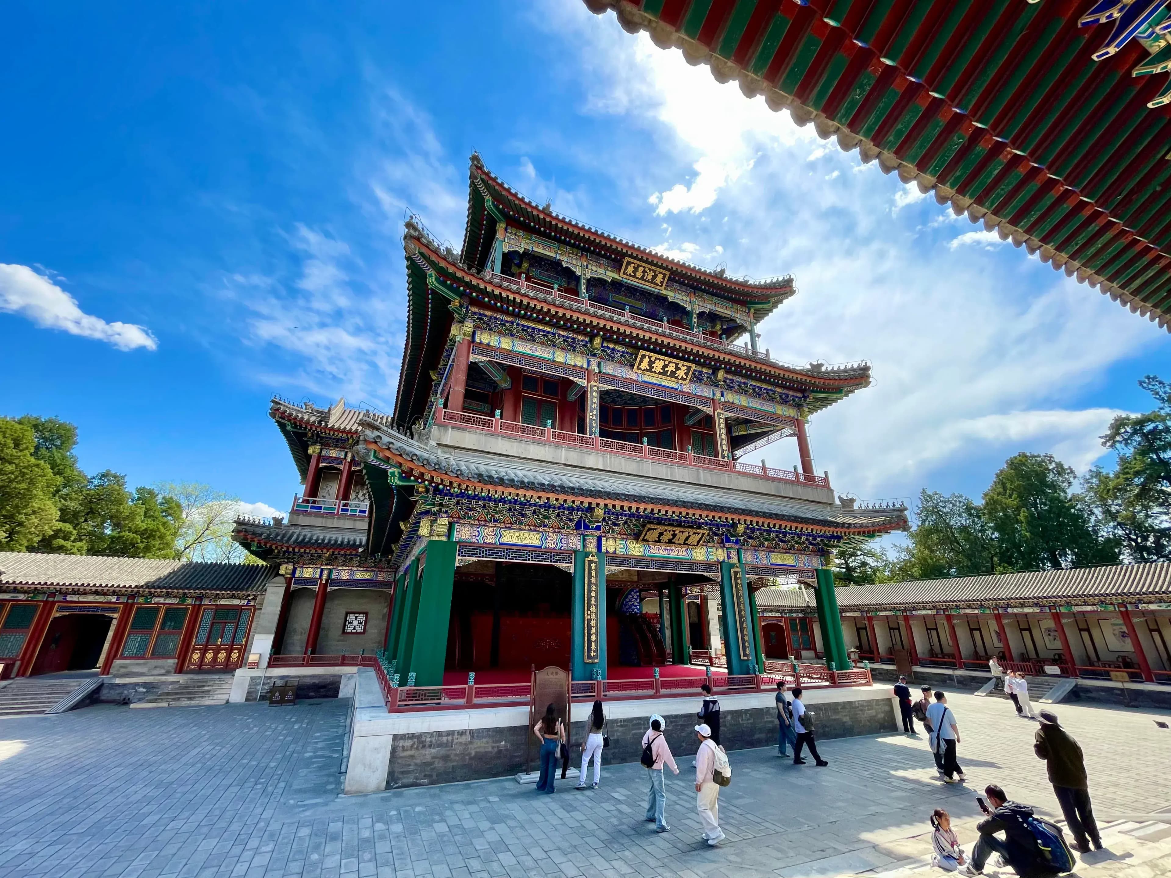 A three-story traditional Chinese opera hall with ornate decorations and a tiled roof, surrounded by visitors.