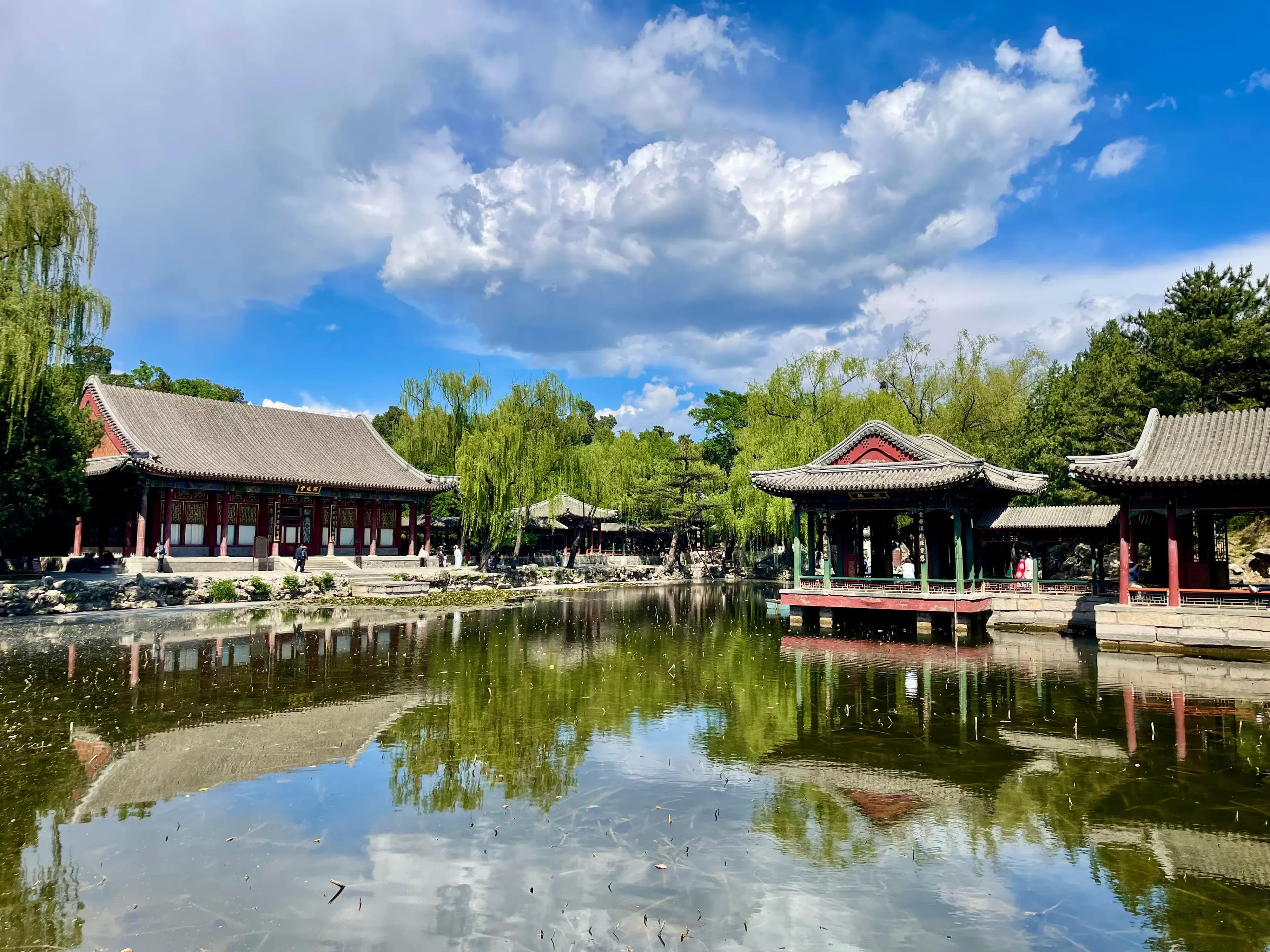Traditional Chinese architecture and serene pond reflecting the buildings and sky.
