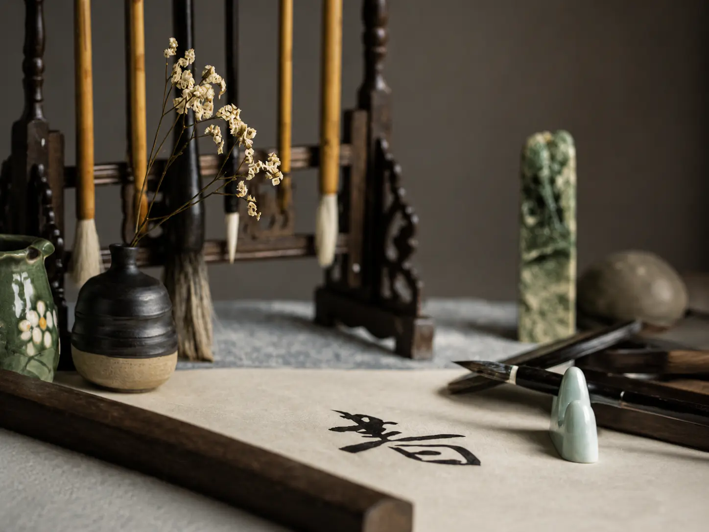 A traditional Chinese calligraphy setup featuring brushes, inkstone, paper with Chinese characters, and decorative elements.