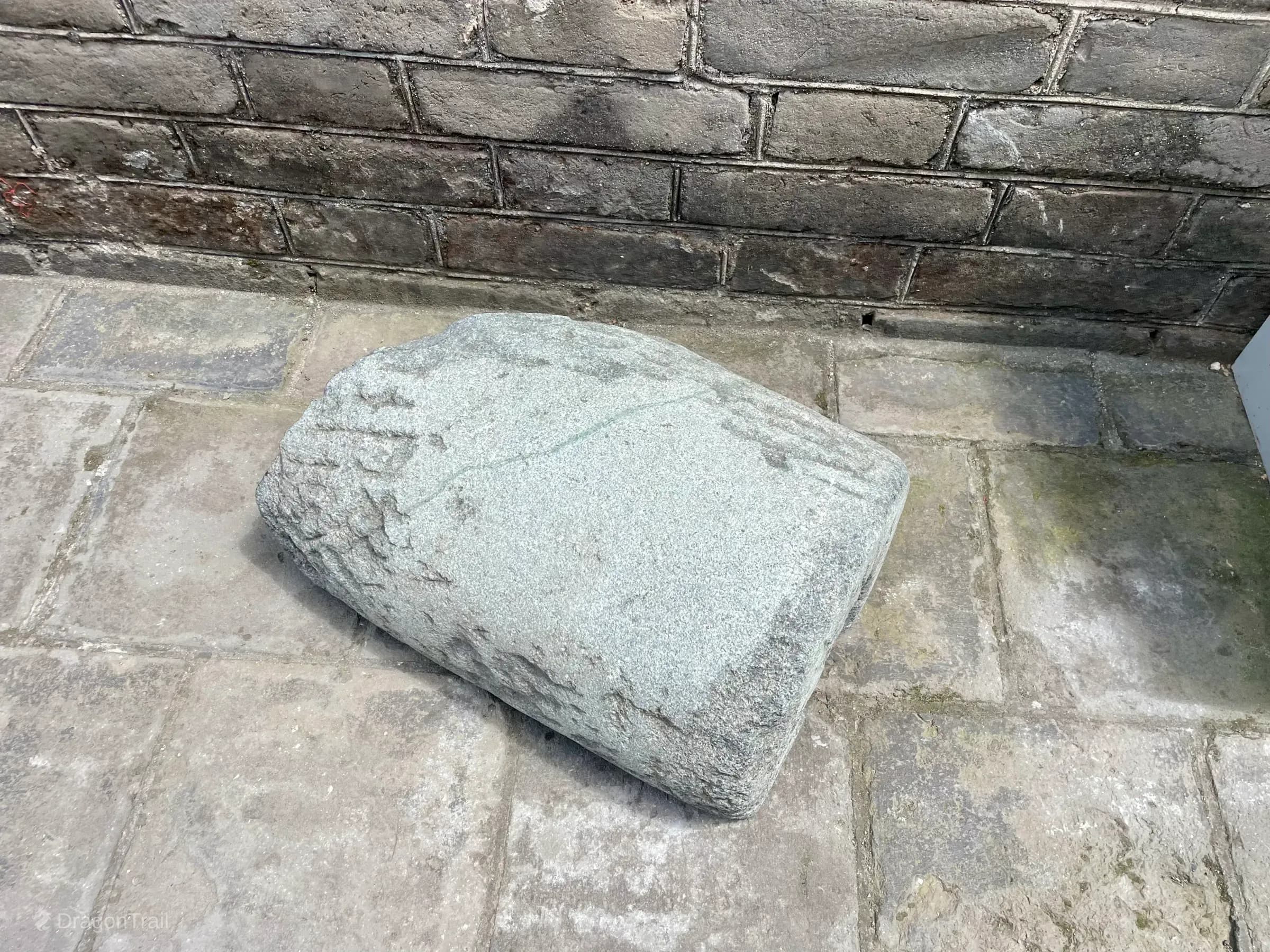Weathered cylindrical stone cannon resting on paved Mutianyu Tower 4 flooring against a brick wall