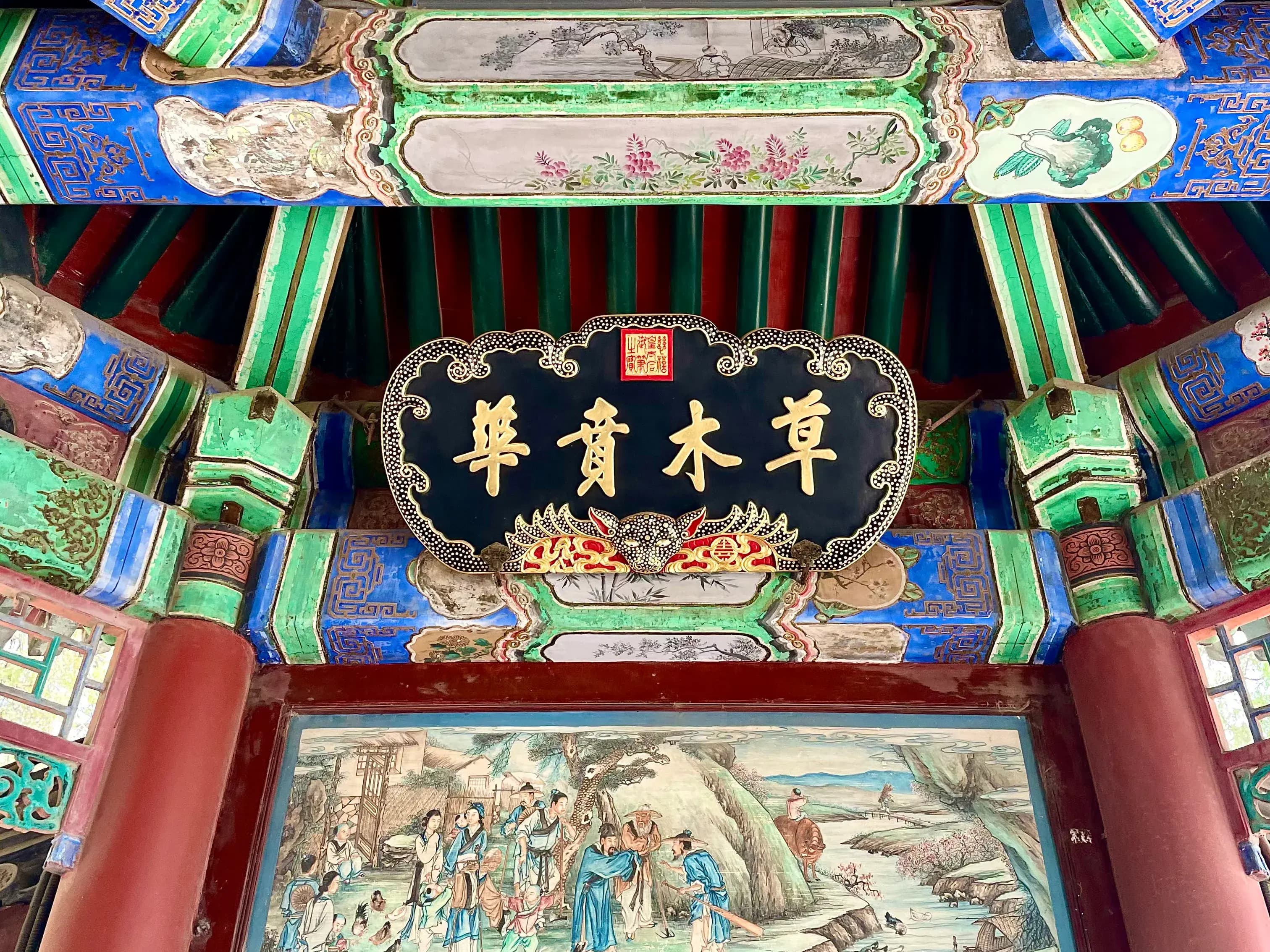 A decorative sign with Chinese characters and a colorful mural depicting a traditional scene.