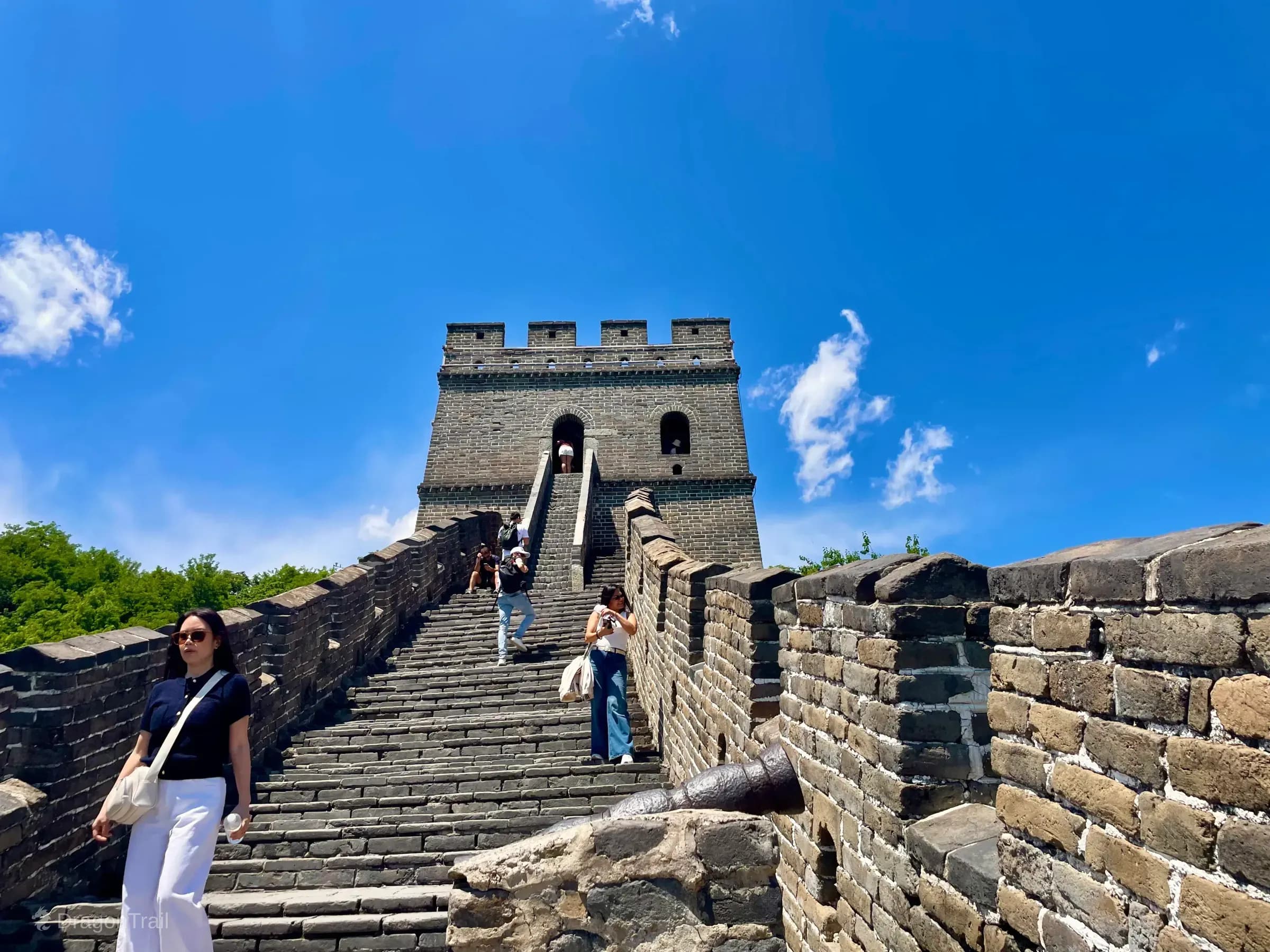 Stone stairs climbing toward Mutianyu Tower 13 with a cannon on the parapet