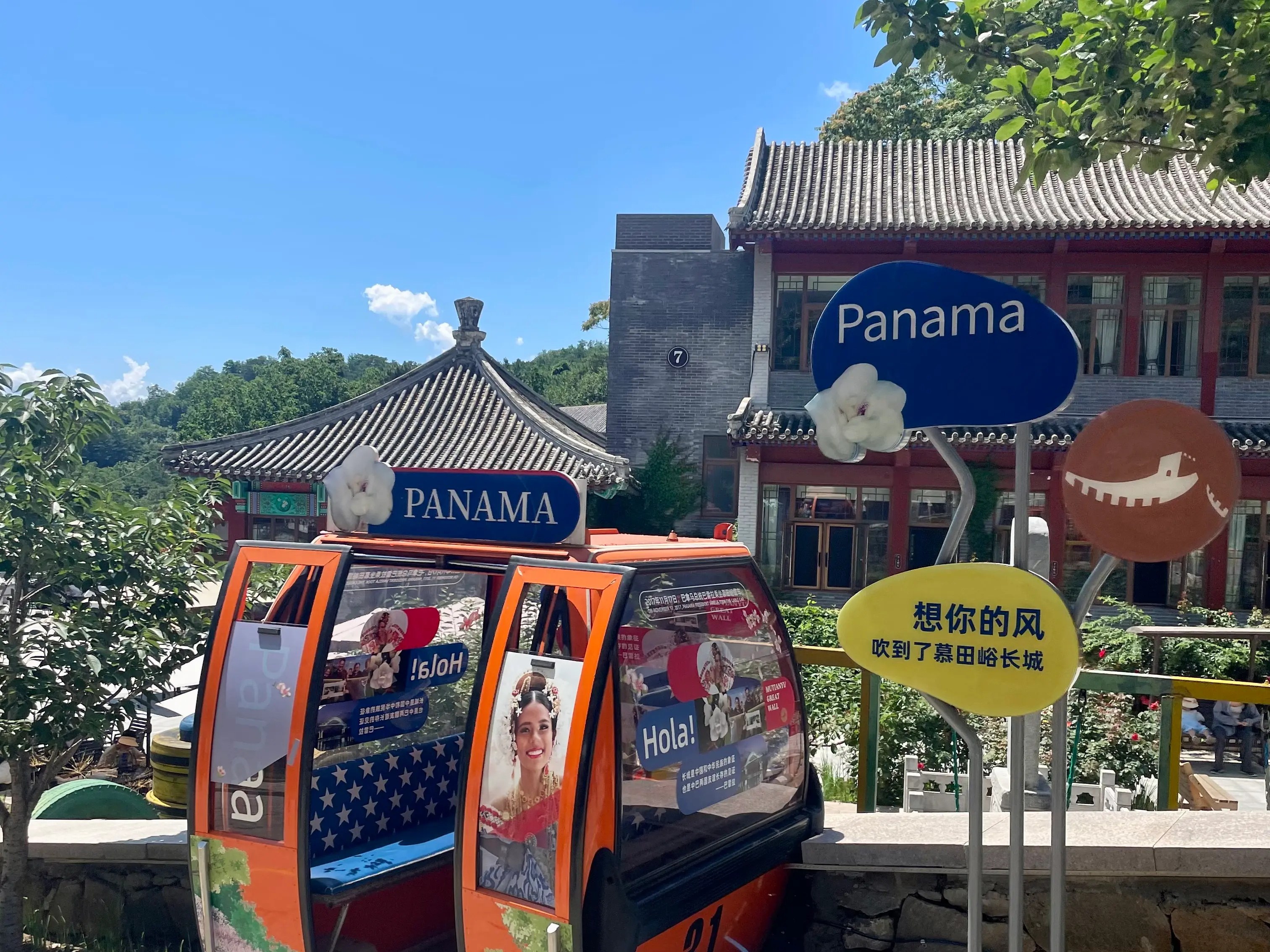 Approach to the Mutianyu Great Wall west route, with a decorative Panama-themed cable car cabin and traditional Chinese-style buildings along the shopping street.