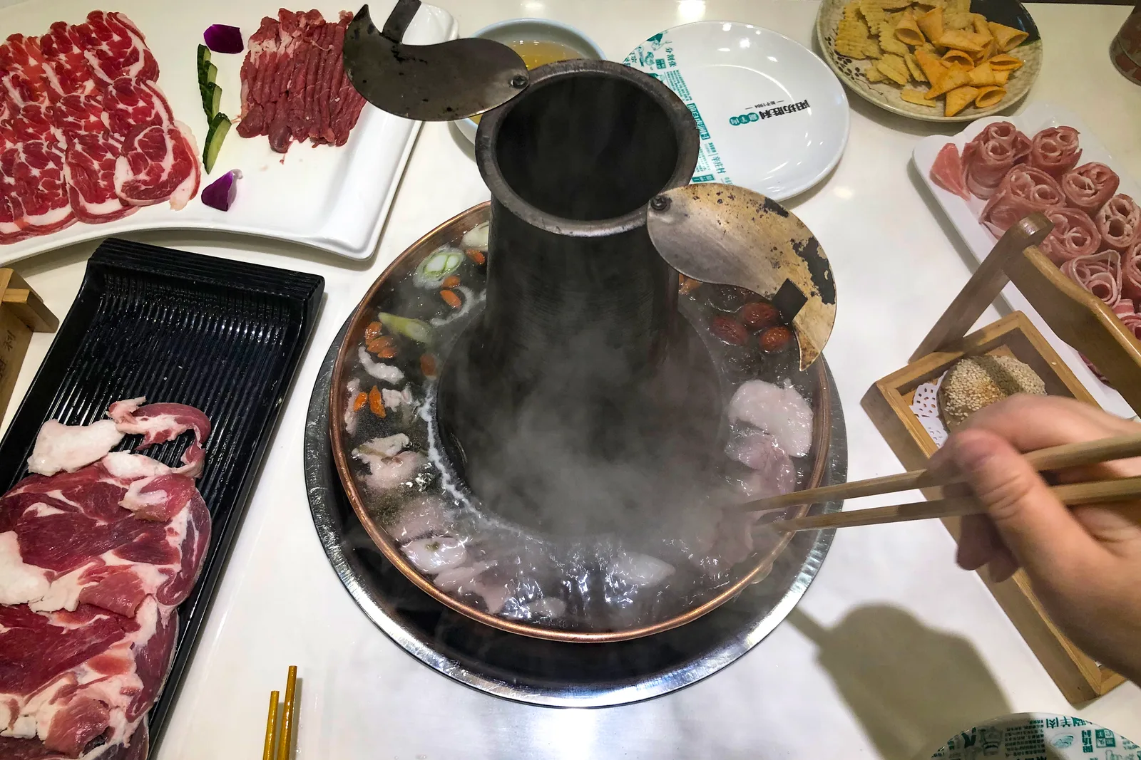 Thin slices of lamb cooking in traditional Beijing hotpot