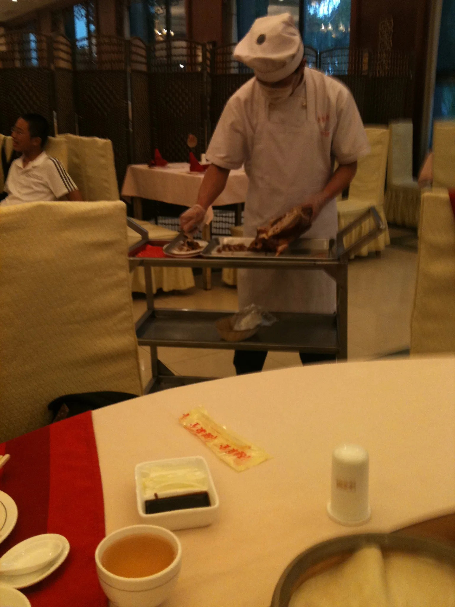 Chef carving Peking duck tableside at a Beijing restaurant