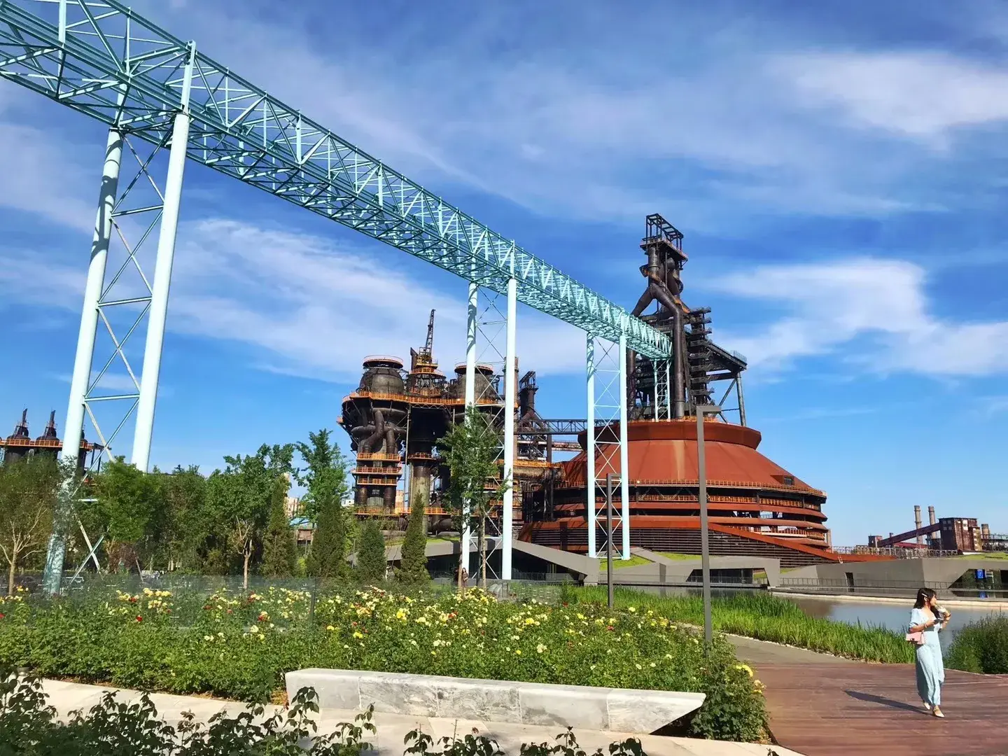 No. 3 blast furnace and light-blue steel gantry above gardens and a wooden boardwalk at Shougang Park, Beijing