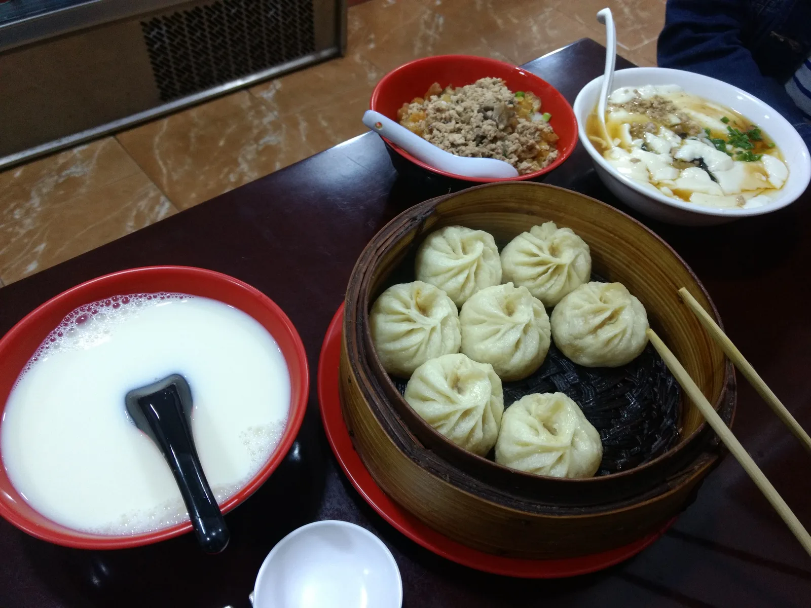 Chinese breakfast spread with buns, congee, pickles and soy milk on a table