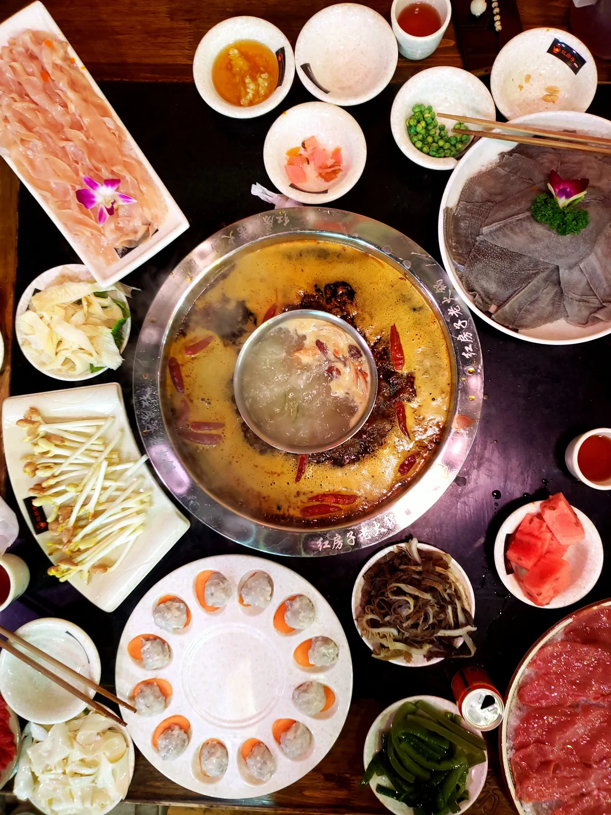 Hotpot broth and ingredients on a restaurant table in Chongqing