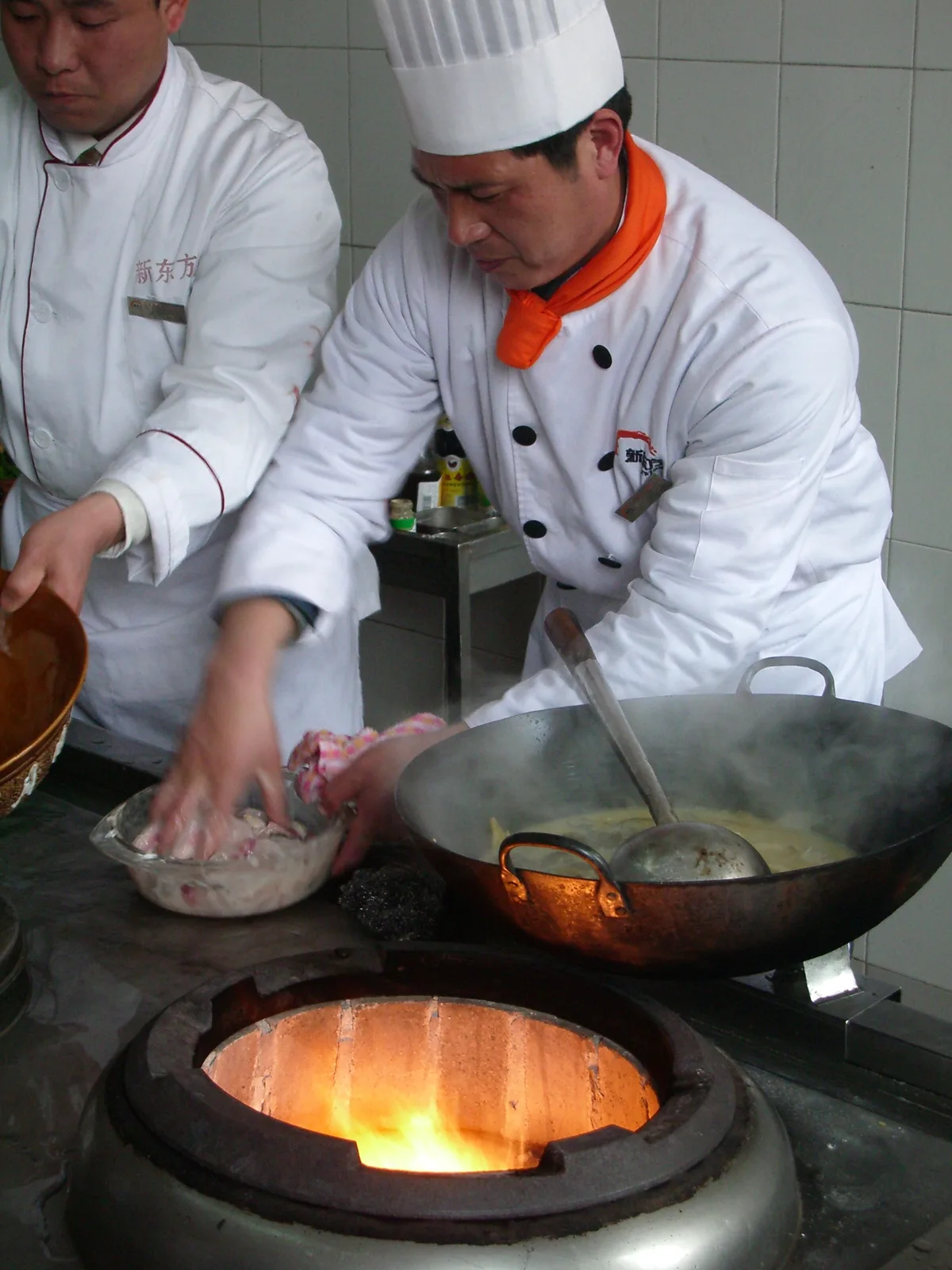 Wok over a high flame during Chinese stir-frying, showing classic curved pan and spatula technique