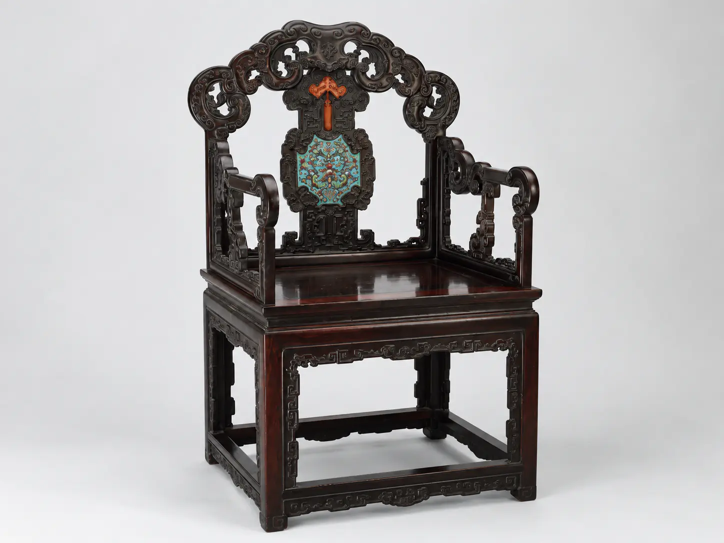 Sillón chino de madera oscura con un respaldo tallado ornamentado
