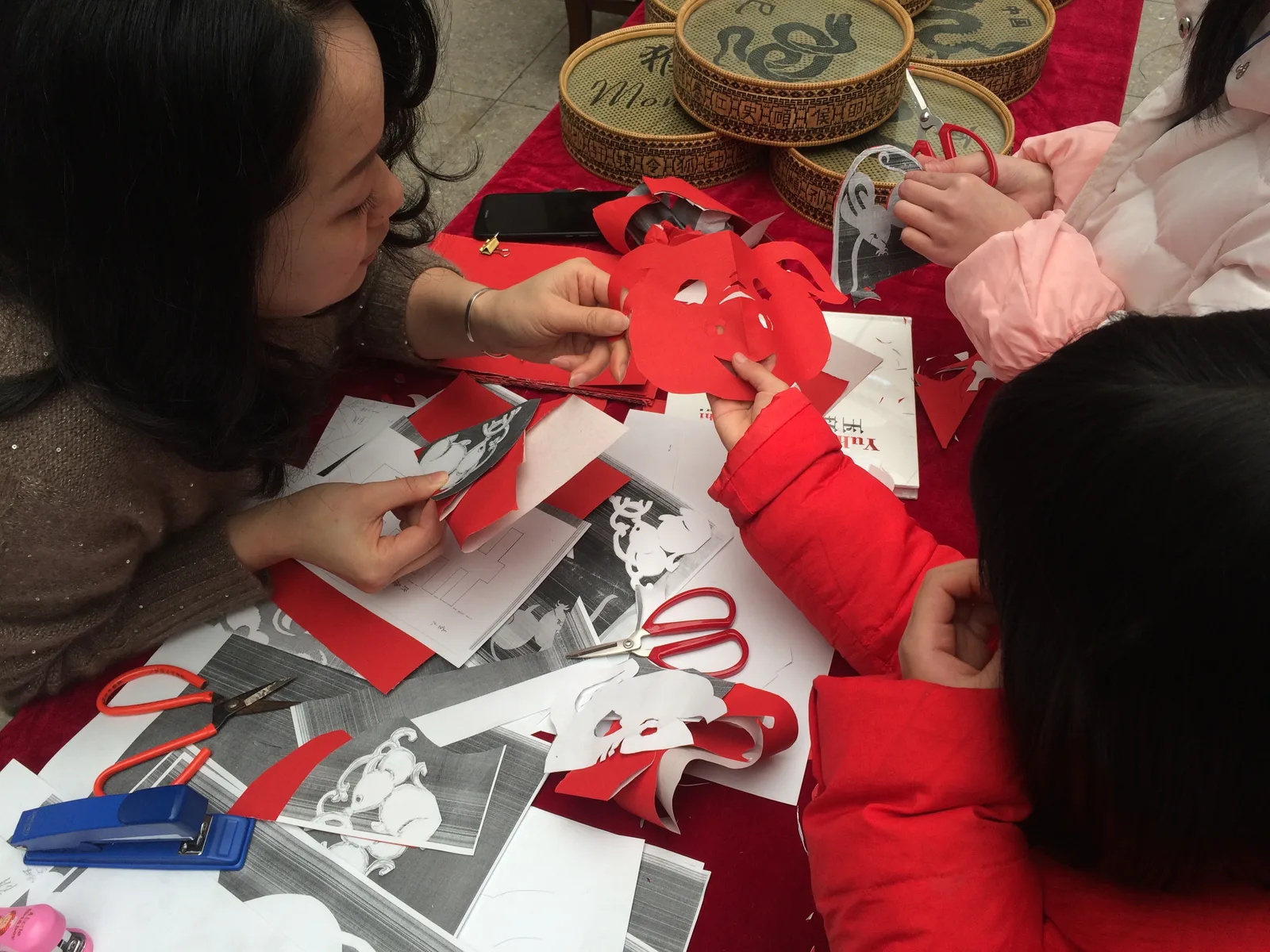 People cutting red paper with scissors in a Chinese paper-cutting activity