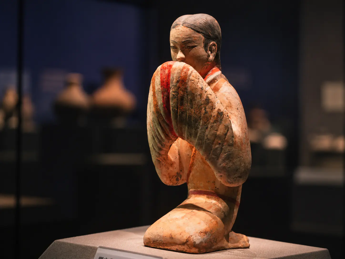Figura de terracota pintada con una prenda larga a rayas