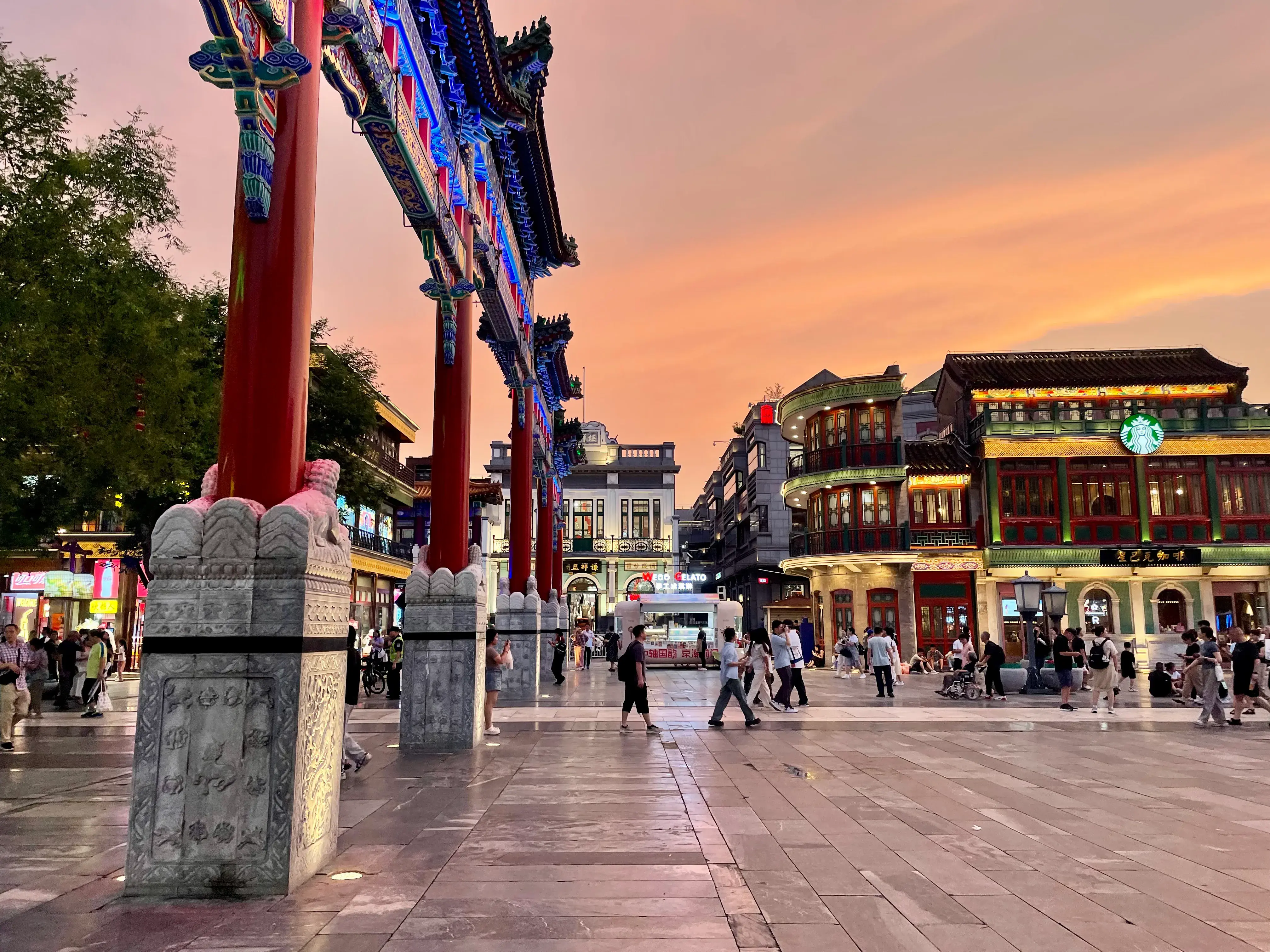 Personas caminando por el distrito peatonal de compras de Qianmen al atardecer
