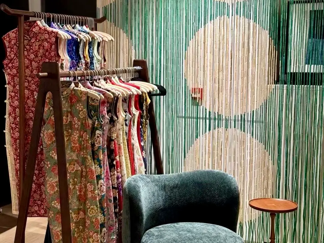 Ropa cheongsam floral colgada en un perchero de madera