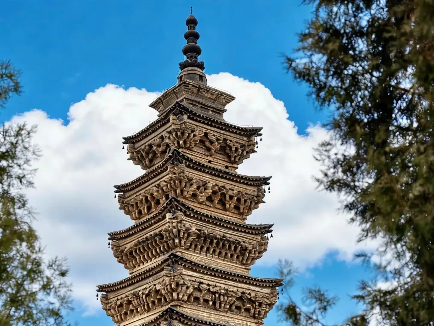 Ornate brick pagoda with wind bells against a blue sky in Xingtai